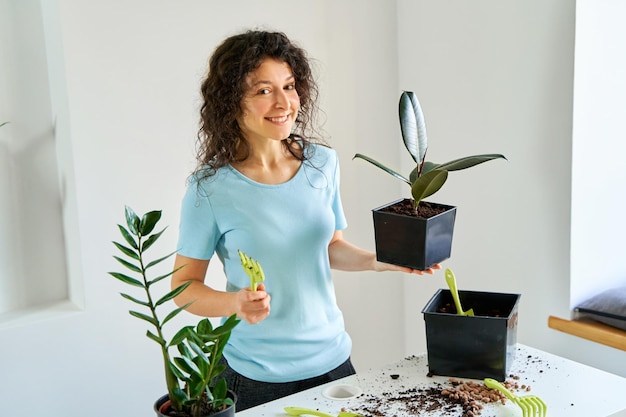 Hausarbeit zum Umpflanzen von Blumen in einen neuen Topf Ein junges Mädchen ist in einer hellen Wohnung mit Blumen beschäftigt