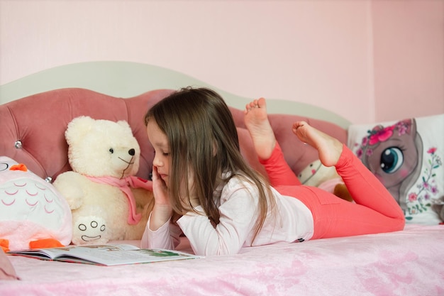 hausaufgaben zum lesen von literatur bei kindern ein kleines mädchen liegt mit einem buch auf dem bett