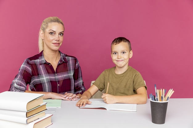 Hausaufgaben zusammen im Quarantänekonzept. Mutter mit Kind, das mit Büchern am Schreibtisch sitzt und studiert.