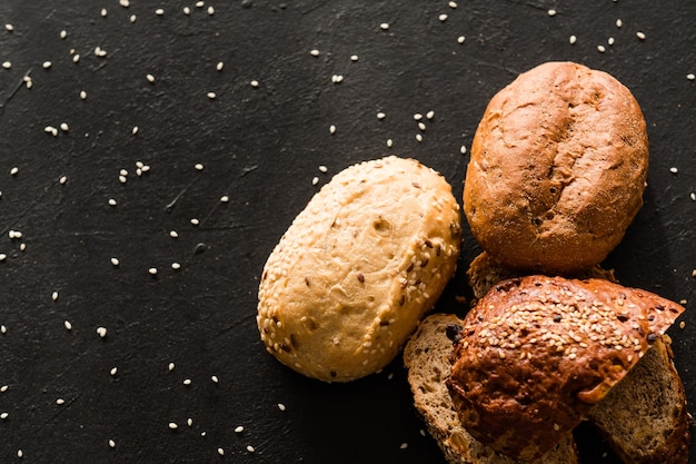 Hausbäckerei. Brotrezeptvielfalt. Verschiedene Stücke mit Sesam auf Schwarz