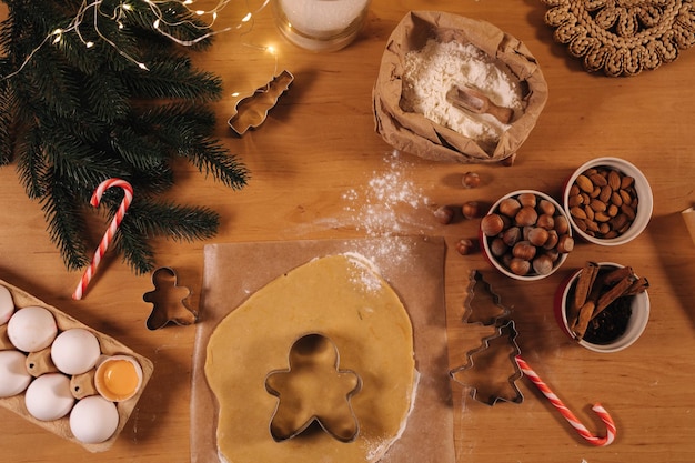 Hausbäckerei, die traditionelle festliche Süßigkeiten kocht, die Kekse aus rohem Lebkuchenteig auf Holz schneiden