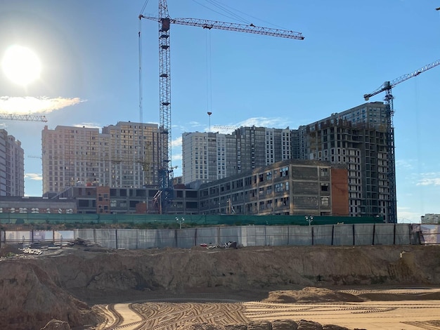 Hausbau mit Baukränen auf einem Hintergrund des blauen Himmels Bau und Reparatur