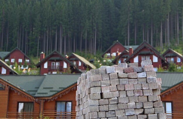 Hausbau. Quadratische Ziegel vor Holzhütten gestapelt