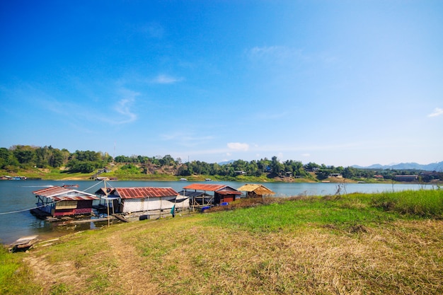 Hausboot im Songgaria-Fluss und nahe Berg in der Landschaft des Dorfs bei Snagklaburi, Thailand