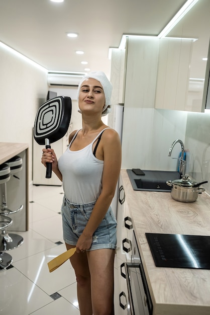 Hausfrau hält Bratpfanne in der Küche vor seltenem Frühstück nach der Dusche