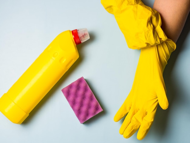 Hausfrau zieht gelbe Latex-Reinigungshandschuhe auf blauem Hintergrund mit Kopierraum an