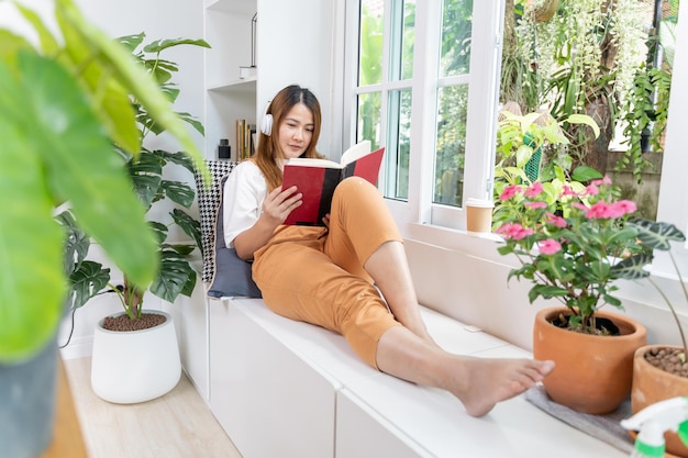 Hausgartenarbeit und Baumpflanzung im Botanischen Garten. Asiatische Frau liest Buch und entspannt sich in der Frühjahrssaison.