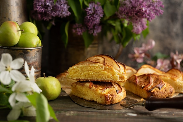 hausgemachte Apfel-Zimt-Scones mit lila Blüten und apfelblühenden Zweigen. Englisches Frühstück oder Brunch im Dorf