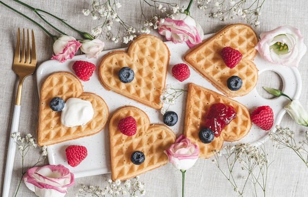 Foto hausgemachte belgische herzwaffeln mit erdbeersauce und beeren