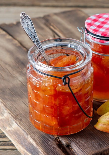 Hausgemachte Birnenmarmelade auf Holzschreibtisch im Hintergrund mit frischen reifen Birnen.