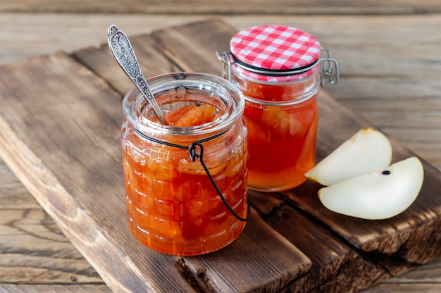 Hausgemachte Birnenmarmelade auf Holzschreibtisch im Hintergrund mit frischen reifen Birnen.