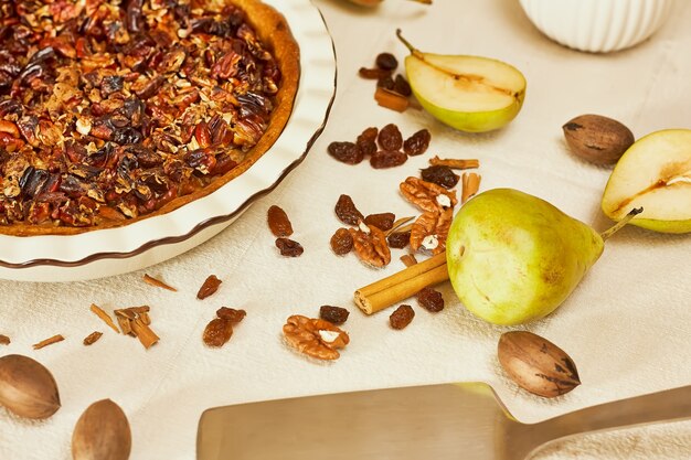 hausgemachte Birnentorte mit frischen Birnen und Pekannüssen auf heller Leinentischdecke