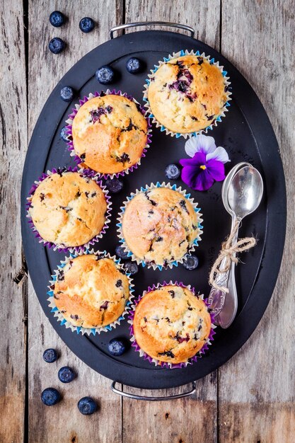 Hausgemachte Blaubeermuffins auf einem Tablett von oben auf einem rustikalen Holzhintergrund