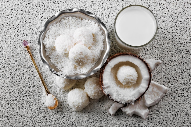 Hausgemachte Bonbons in Kokosflocken und frischer Kokosnuss auf hellem Hintergrund