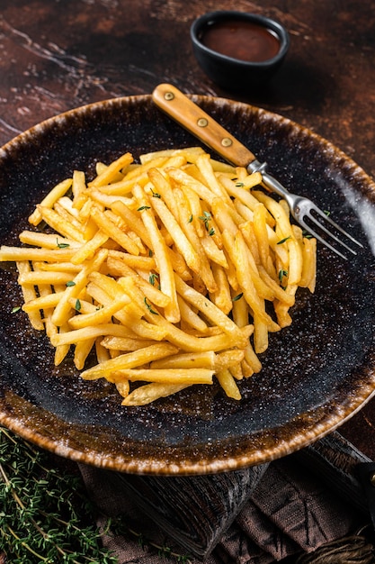 Hausgemachte Bratkartoffel Pommes Frites in rustikaler Geschmacksrichtung mit Thymian. Dunkler Hintergrund. Ansicht von oben.