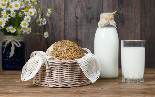 Foto hausgemachte brotmilch und blumenstrauß aus gänseblümchen auf holztisch