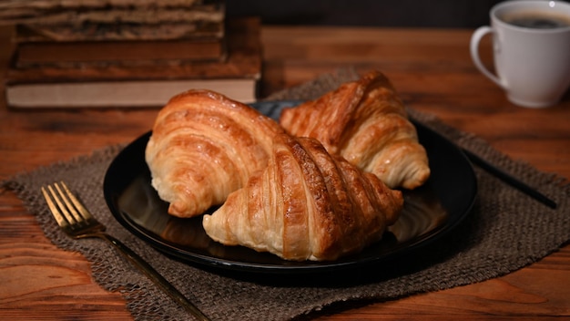 Hausgemachte Buttercroissants auf Holztisch mit Kaffeetasse zum Frühstück