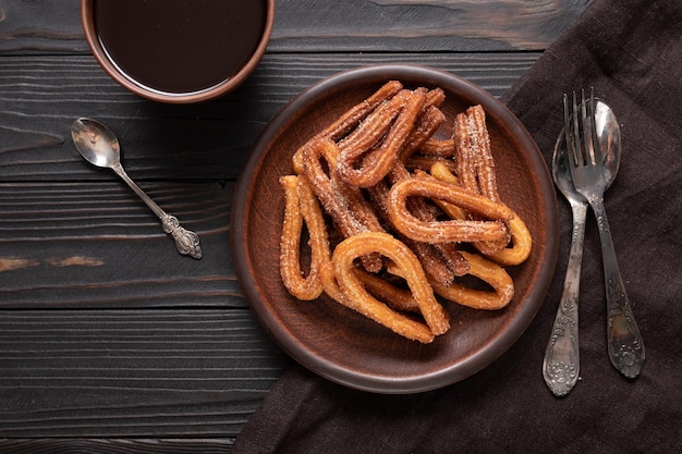 Hausgemachte Churros mit Schokolade auf dunklem rustikalem Holzhintergrund