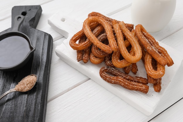 Hausgemachte Churros mit Schokolade auf weißem Holzhintergrund