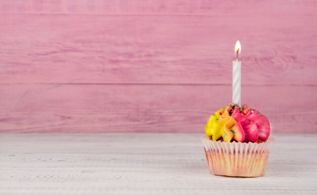 Hausgemachte Cupcakes mit mehrfarbiger Creme auf einem rosa Hintergrund kopieren Raum. Gelbe und rosa Creme.