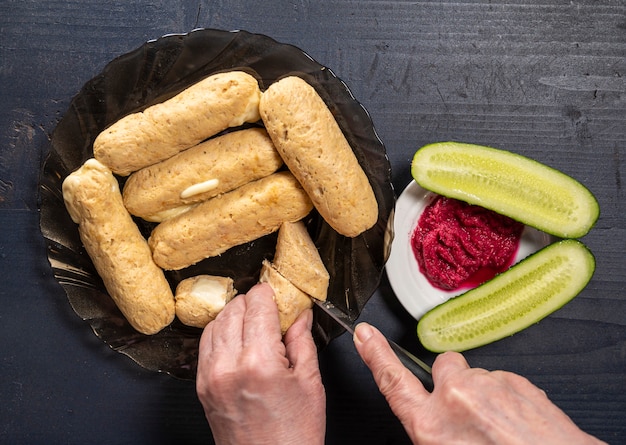 Hausgemachte diätetische Hühnerwürste, Gurken und Rübenwurzelwurst auf einem Holztisch