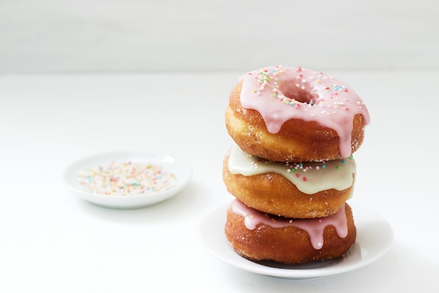 Hausgemachte Donuts verziert mit farbigem Zuckerguss und farbigem Zucker auf hellem Hintergrund.