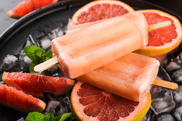 Hausgemachte Eis am Stiel der roten Grapefruit mit Eiswürfeln.
