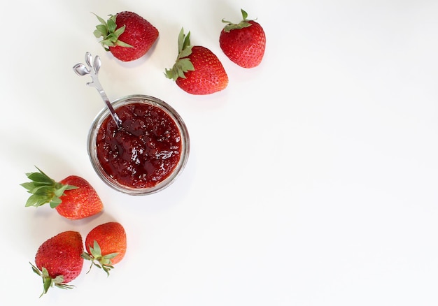 Hausgemachte Erdbeerkonserven oder Marmelade in einem Einmachglas, umgeben von frischen Bio-Erdbeeren Selektiver Fokus mit weißem Hintergrund