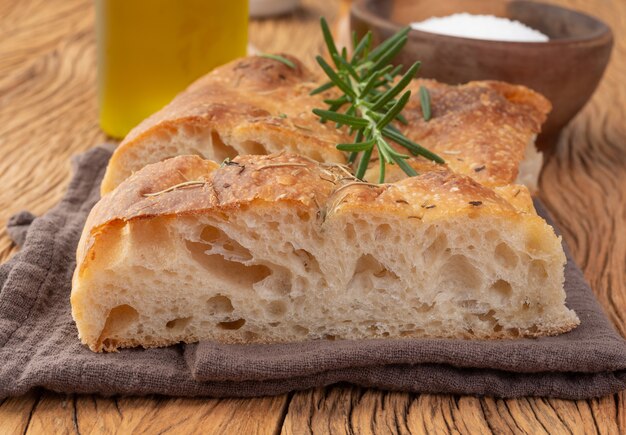 Hausgemachte Focaccia mit Salz, Olivenöl und Rosmarin über Holztisch.