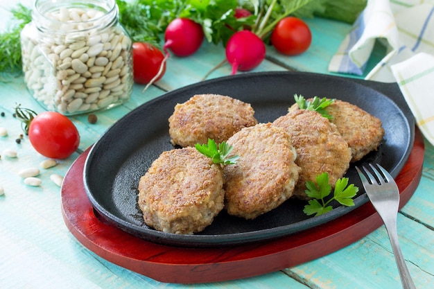 Hausgemachte Frikadellen mit weißen Bohnen und frischen Kräutern Bratpfanne aus Gusseisen