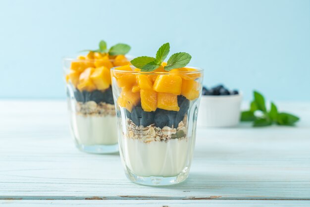 hausgemachte frische Mango und frische Blaubeere mit Joghurt und Müsli - gesunde Ernährung