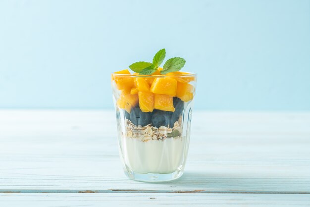 hausgemachte frische Mango und frische Blaubeere mit Joghurt und Müsli - gesunde Ernährung