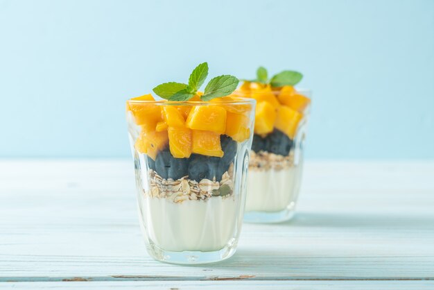 hausgemachte frische Mango und frische Blaubeeren mit Joghurt und Müsli - gesunde Ernährung