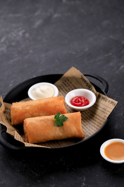 Hausgemachte Frühlingsrolle, gefüllt mit Hühnchen und Garnelen, serviert mit saurer und süßer Sauce. Serviert auf schwarzem Teller mit schwarzem Hintergrund. Platz für Text kopieren