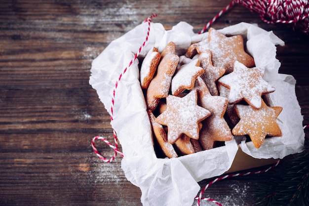 Hausgemachte gebackene Weihnachtslebkuchenplätzchen mit Puderzucker in der Schachtel auf Holzhintergrund