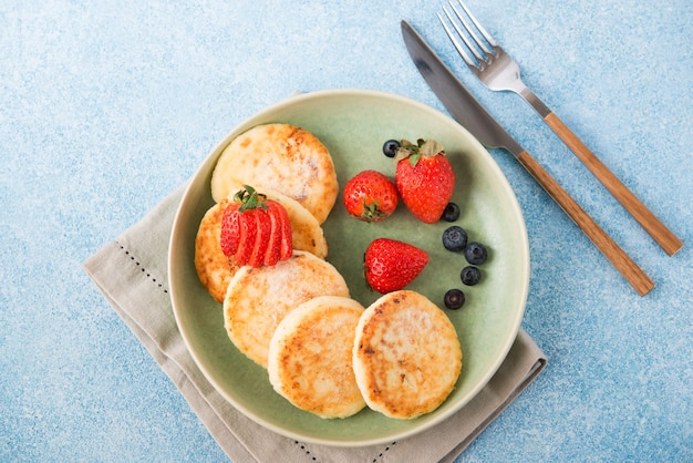 Hausgemachte gebratene Käsekuchen mit Kondensmilch und Beeren, Draufsicht