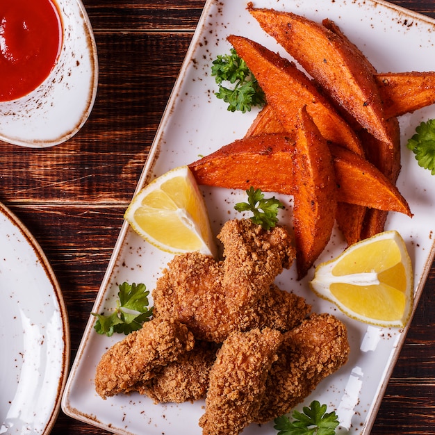 Hausgemachte gekochte Hicken Nuggets und Süßkartoffeln.