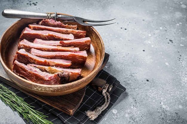 Hausgemachte geräucherte Schweinerippchen vom Grill in Holzplatte zum Essen bereit Grauer Hintergrund Ansicht von oben Kopieren Sie Platz