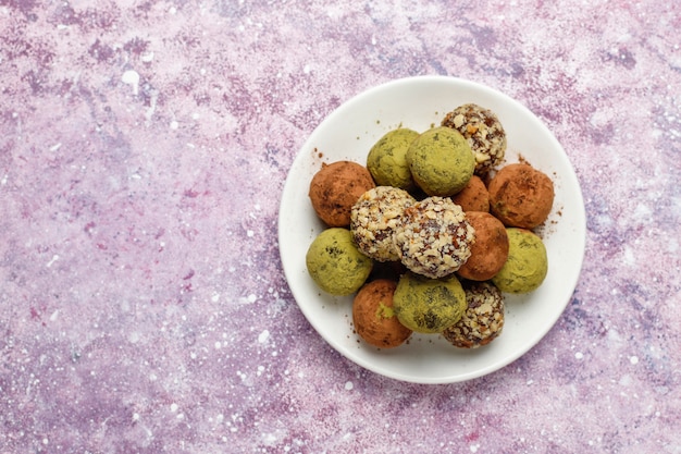 Hausgemachte gesunde vegane rohe Energie-Trüffelbällchen mit Datteln und Walnüssen, Matcha-Pulver, Kakaopulver