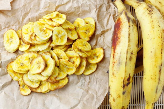 Hausgemachte getrocknete Bananenchips auf Draufsicht des rustikalen Papierblatts