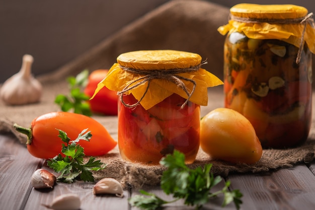 Hausgemachte Gläser mit eingelegten Paprika auf einem rustikalen Holzhintergrund in Essig eingelegt und Konserven neben anderen