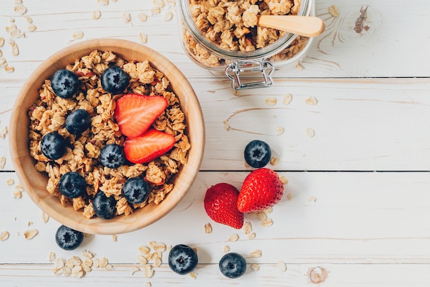 Hausgemachte Granola und frische Beeren auf Holztisch mit Platz.