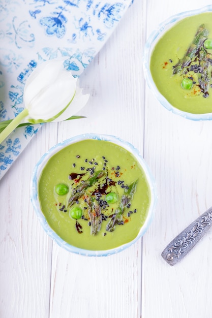 Hausgemachte grüne Sahnesuppe mit Spargel und grünen Erbsen, Draufsicht