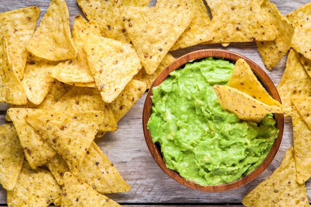 Hausgemachte Guacamole mit Draufsicht auf Maischips auf rustikalem Holztisch