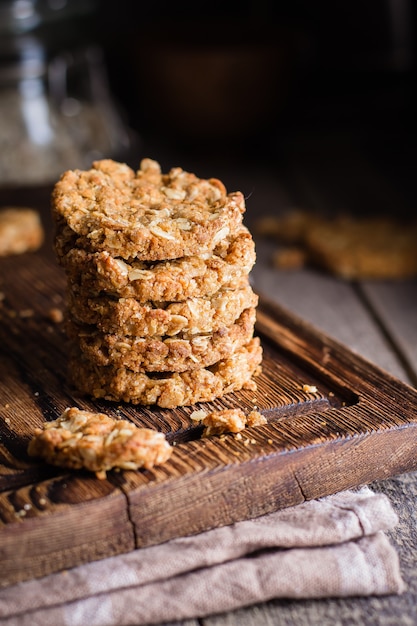 Hausgemachte Haferkekse auf Holzbrett auf altem Tisch. Gesundes Lebensmittel-Snack-Konzept. Speicherplatz kopieren /