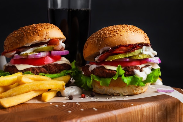 Hausgemachte Hamburger auf einer Tafel auf einem schwarzen Hintergrund