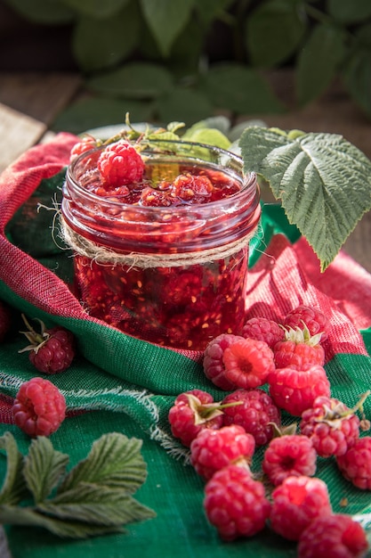 Hausgemachte Himbeermarmelade im Marmeladenglas rohe Himbeeren auf einer grünen Serviette