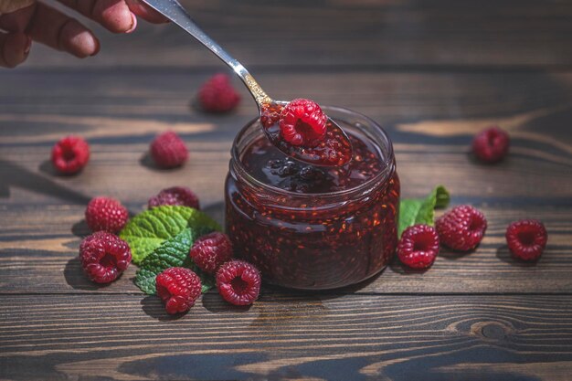 Hausgemachte Himbeermarmelade oder Marmelade im Glas und reife Himbeeren auf dem Holztisch