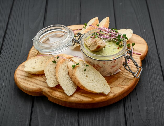 Hausgemachte Hühnerleberpastete im Glas auf einem rustikalen Holztisch