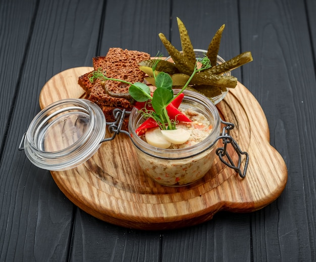 Hausgemachte Hühnerleberpastete im Glas auf einem rustikalen Holztisch